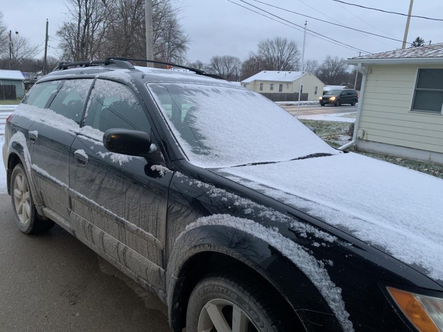 A car is covered in snow before it is cleaned.