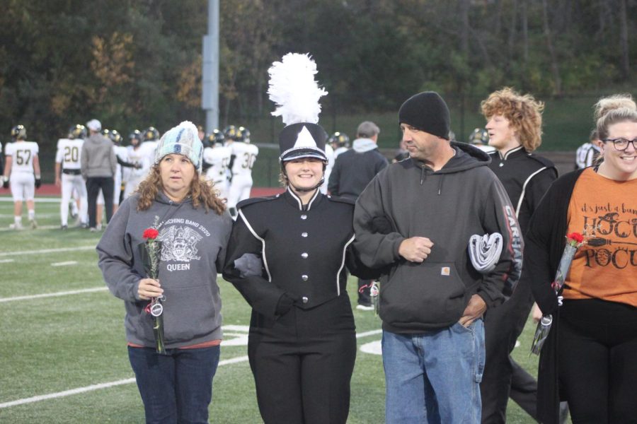 Madison stands with her parents at a marching band performance. 
