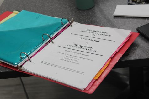 A binder filled with Mock Trial materials lays on the table to be referenced during a meeting. Every student has a booklet like this one that has all of the information needed about the case, exhibits, and witnesses. This student highlighted, marked up, and used sticky notes to organize the trial notes. 