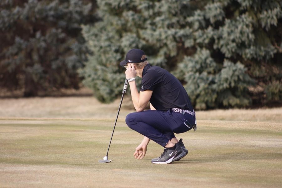 Easton Korell, a Junior golfer, scopes out his putt line on hole 17 at River Valley.