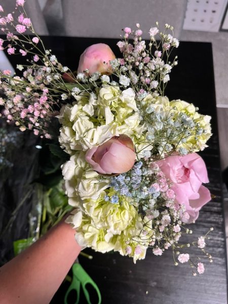 A fresh bouquet of flowers, made up of peonies, hydrangeas, and colored babys breath. 