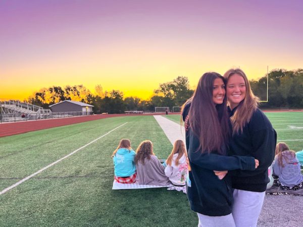 Posing to get their picture taken, seniors, Allison Blum and Hannah Desmarais hugging in front of the sky. 