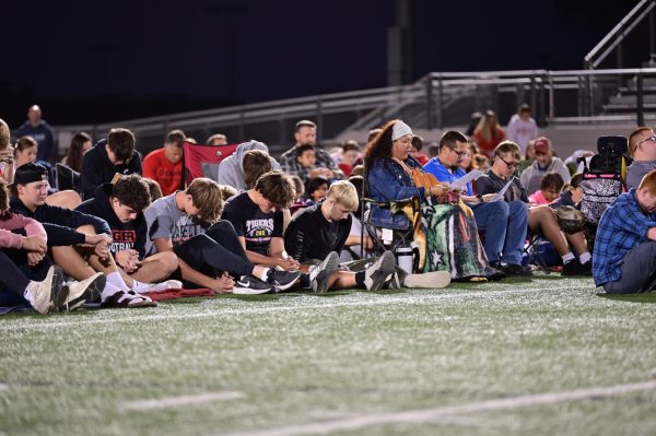 Students and families bow down their heads in prayer.