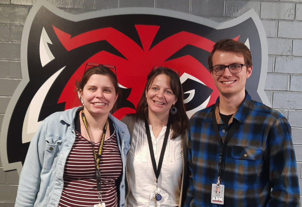Pictured from left to right, Chloe Safley, Carrie Laizure and Gabriel Laizure stand in front of ADM’s tiger logo located in the high school commons. These three educators have a special, interconnected story, and it is one unbeknownst to many high school students who come to school here each day. 