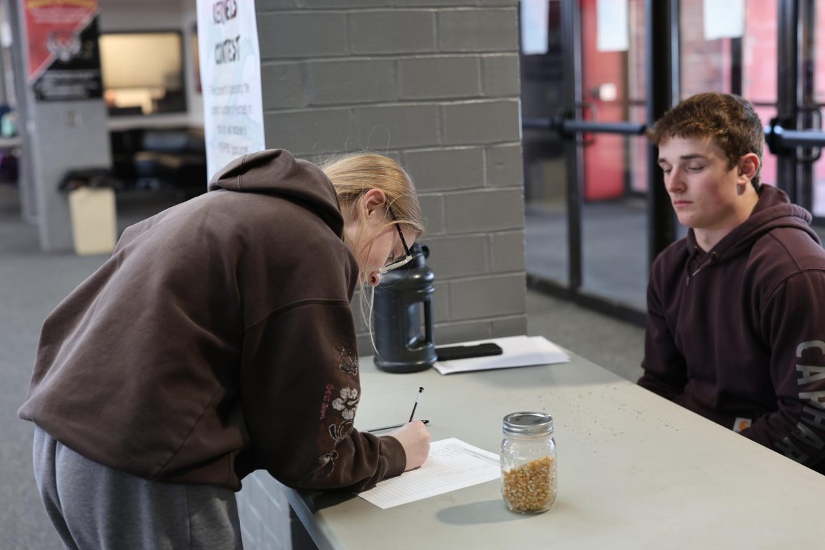 Hanna Widen guesses how many corn kernels are in a jar, while Zachary Bass, a sophomore on the FFA officer team, offers advice. The officer team prepared for FFA week by meeting twice a week to coordinate events, and come up with ideas. When asked about his time as an FFA Officer so far, Bass said "I've learned how to be that team leader, and it's shaped me as an overall person and taught me a lot of good qualities."